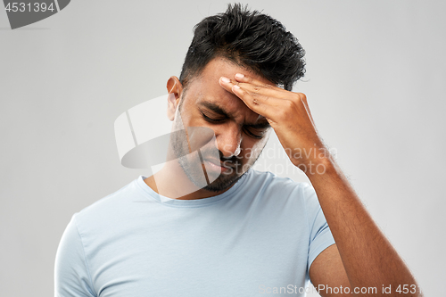 Image of unhappy indian man suffering from headache