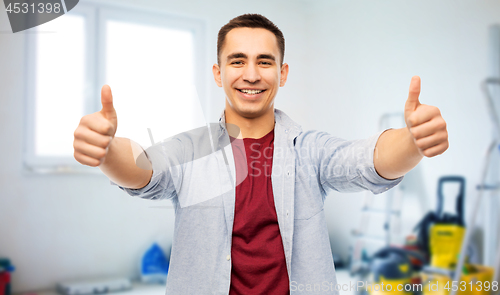 Image of happy young man showing thumbs up over home repair