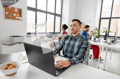 Image of creative man with laptop working at office