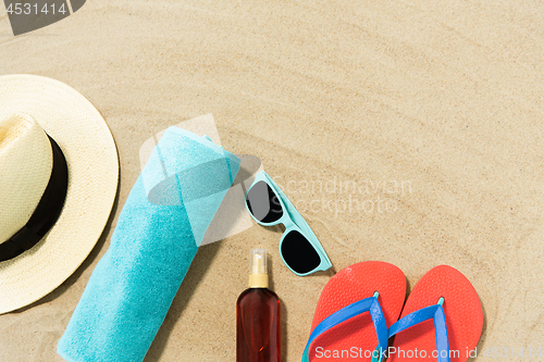 Image of straw hat, flip flops and sunglasses on beach sand