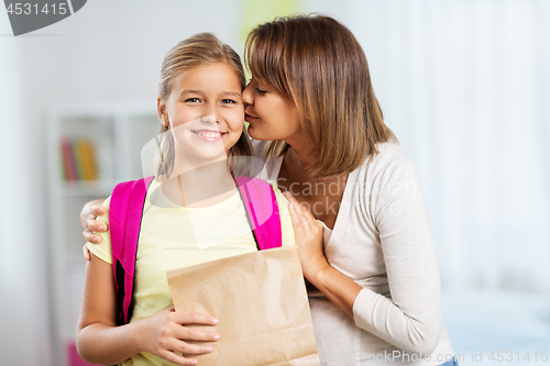 Image of loving mother giving daughter school lunch at home