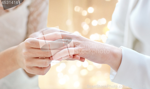 Image of close up of lesbian couple hands with wedding ring