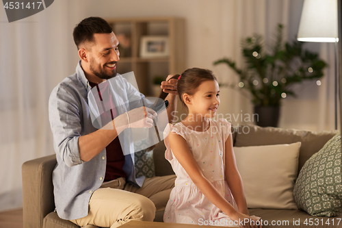 Image of father brushing daughter hair at home