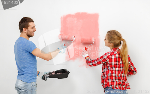 Image of happy couple painting wall at home