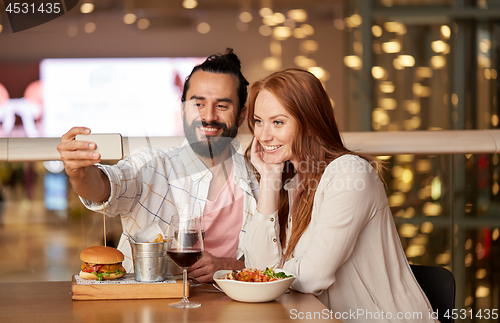 Image of couple taking selfie by smartphone at restaurant