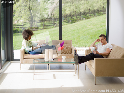 Image of multiethnic couple relaxing at  home with laptop computers