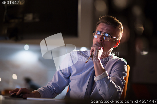 Image of man working on computer in dark office