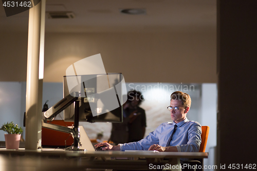 Image of man working on computer in dark office