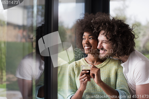 Image of happy multiethnic couple relaxing at modern home indoors