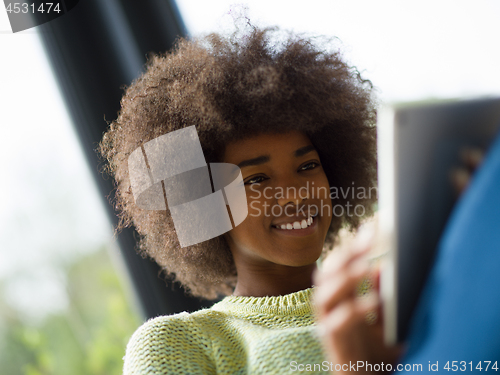 Image of young african american woman at home using digital tablet