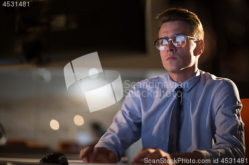 Image of man working on computer in dark office