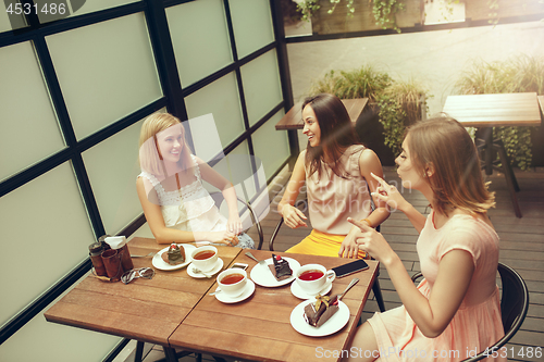 Image of Two girl friends spend time together drinking coffee in the cafe, having breakfast and dessert.