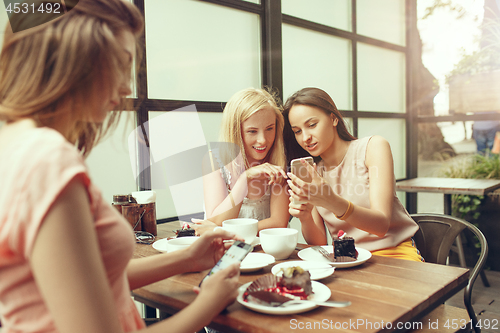 Image of Two girl friends spend time together drinking coffee in the cafe, having breakfast and dessert.