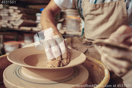 Image of Creating a jar or vase of white clay close-up. Master crock. Man hands making clay jug macro.