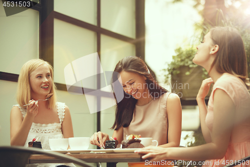 Image of Two girl friends spend time together drinking coffee in the cafe, having breakfast and dessert.