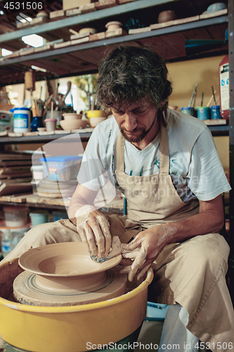 Image of Creating a jar or vase of white clay close-up. Master crock.