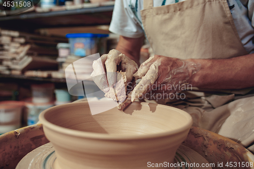 Image of Creating a jar or vase of white clay close-up. Master crock. Man hands making clay jug macro.