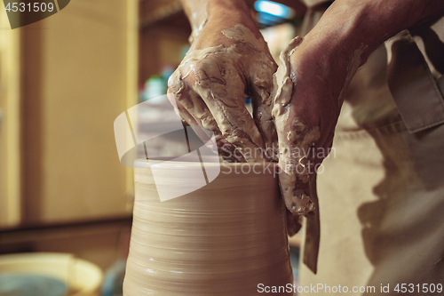 Image of Creating a jar or vase of white clay close-up. Master crock. Man hands making clay jug macro.