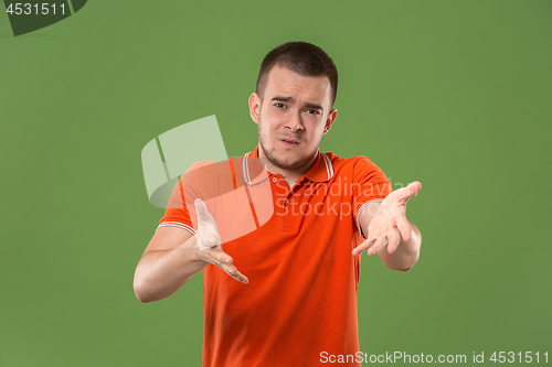 Image of Beautiful male half-length portrait isolated on green studio backgroud. The young emotional surprised man