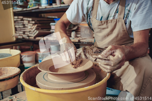 Image of Creating a jar or vase of white clay close-up. Master crock. Man hands making clay jug macro.