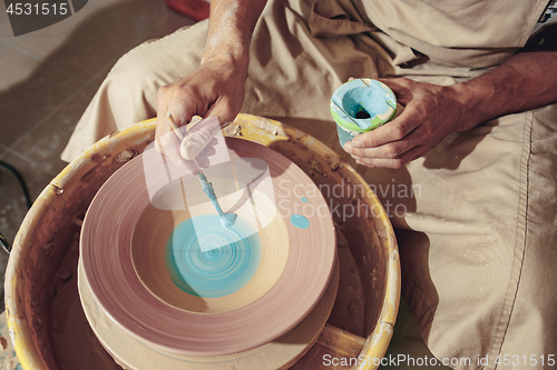 Image of Creating a jar or vase of white clay close-up. Master crock. Man hands making clay jug macro.