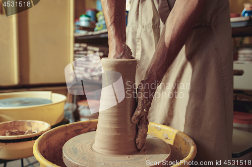 Image of Creating a jar or vase of white clay close-up. Master crock. Man hands making clay jug macro.