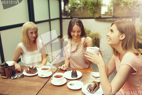 Image of Two girl friends spend time together drinking coffee in the cafe, having breakfast and dessert.