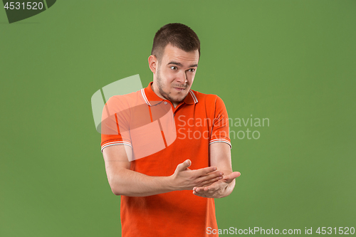 Image of Beautiful male half-length portrait isolated on green studio backgroud. The young emotional surprised man