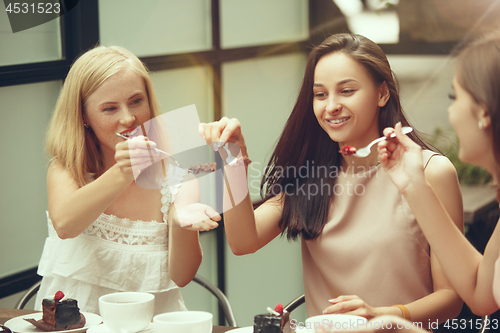 Image of Two girl friends spend time together drinking coffee in the cafe, having breakfast and dessert.