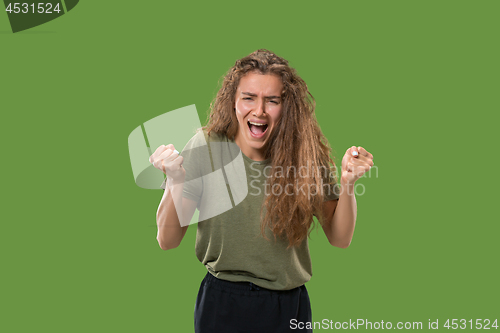 Image of The young emotional angry woman screaming on green studio background