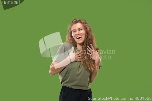 Image of The happy woman standing and smiling against green background.