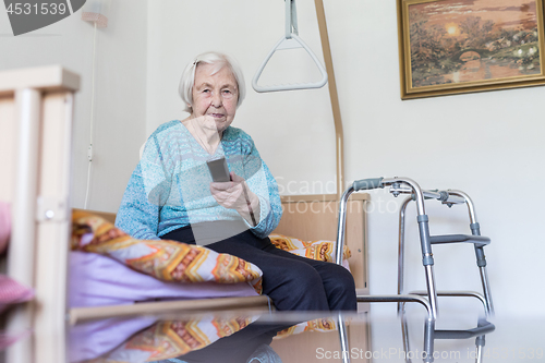 Image of Elderly 96 years old woman operating TV or DVD with remote control