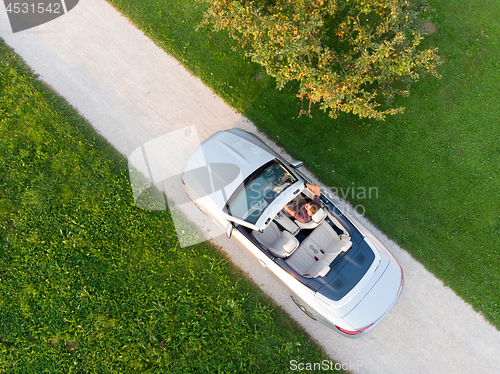 Image of Aerial view of successful man driving and enjoying his silver convertible luxury sports car on the open country side road