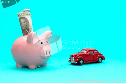 Image of Pink piggy bank with a car on the table. Tinted. Concept of saving finances and contributions to property.