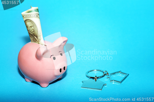 Image of Pink piggy bank with a house on the table. Tinted. Concept of saving finances and real estate deposits.