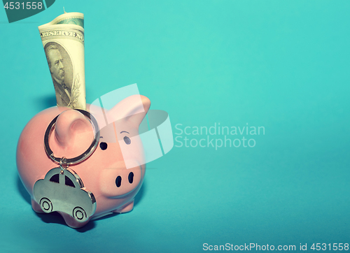 Image of Pink piggy bank with a car on the table. Tinted. Concept of saving finances and contributions to property.