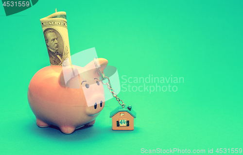 Image of Pink piggy bank with a house on the table. Tinted. Concept of saving finances and real estate deposits.