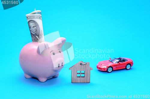 Image of Pink piggy piggy bank with a house and a car on the table. Tinted. Concept of saving finances and real estate deposits.