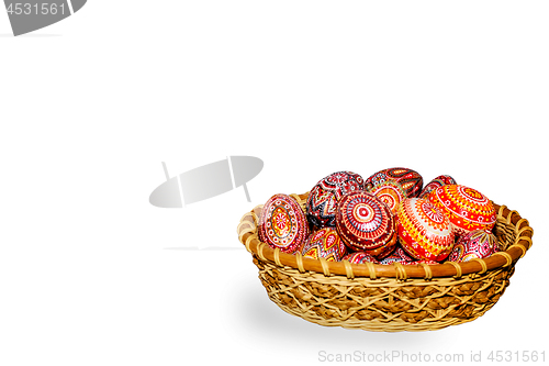 Image of Wooden Easter eggs in a wicker basket, hand-painted with acrylic paints, isolated on a white background.