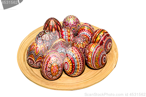 Image of Wooden Easter eggs on a wooden plate, painted with patterns, hand-painted with acrylic paints, isolated on a white background.