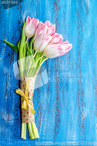 Image of Bouquet of pink tulips on a blue wooden background, space for th