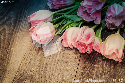 Image of Bouquet of pink tulips on the background of old wooden boards with a place for the inscription, toned