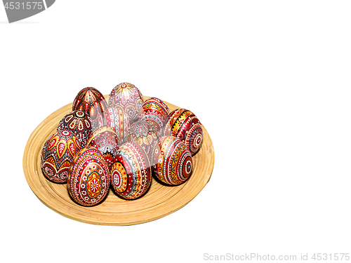 Image of Wooden Easter eggs on a wooden plate, painted with patterns, hand-painted with acrylic paints, isolated on a white background.