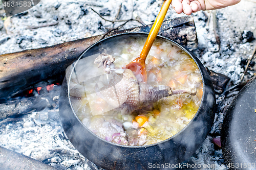 Image of Soup is cooked in a tourist pot on the fire