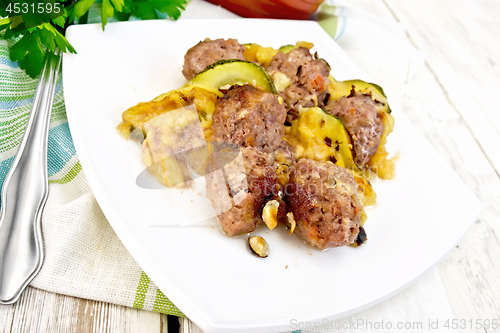 Image of Meatballs with zucchini and nuts in plate on light board