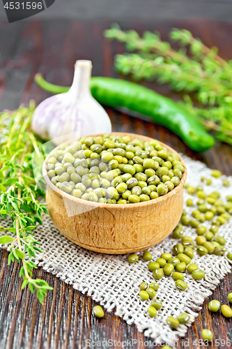 Image of Mung beans in wooden bowl with thyme on burlap