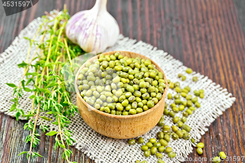 Image of Mung beans in wooden bowl with thyme on dark board