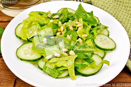 Image of Salad from spinach and cucumber with napkin on wooden board