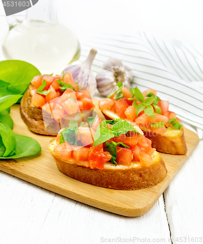 Image of Bruschetta with tomato and spinach on light wooden table