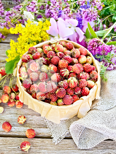Image of Strawberries in box with flowers on wooden board